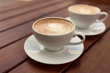 Two cups of cappuccino on the wooden background
