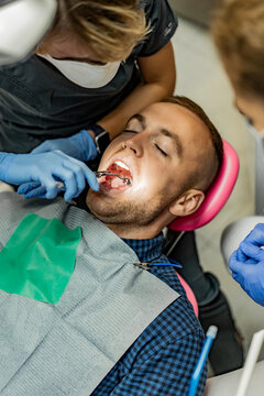 Patient with a kofferdam is being treated by a dentist.Dentist performs dental treatment by putting an injection to a smiling patient.