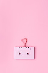 Retro Cassette Tape on a baby rose background. Pink cassette tape with a drawn heart-shaped tape. Minimalist art photography inspired by retro times and music.