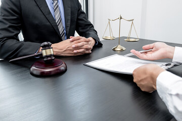 A male lawyer or a judge counseling clients about judicial justice and prosecution with scales, judges gavel, legal documents legal services concept