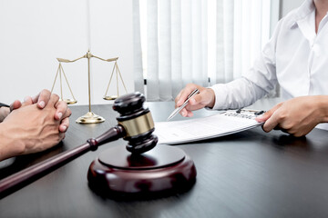 A male lawyer or a judge counseling clients about judicial justice and prosecution with scales, judges gavel, legal documents legal services concept