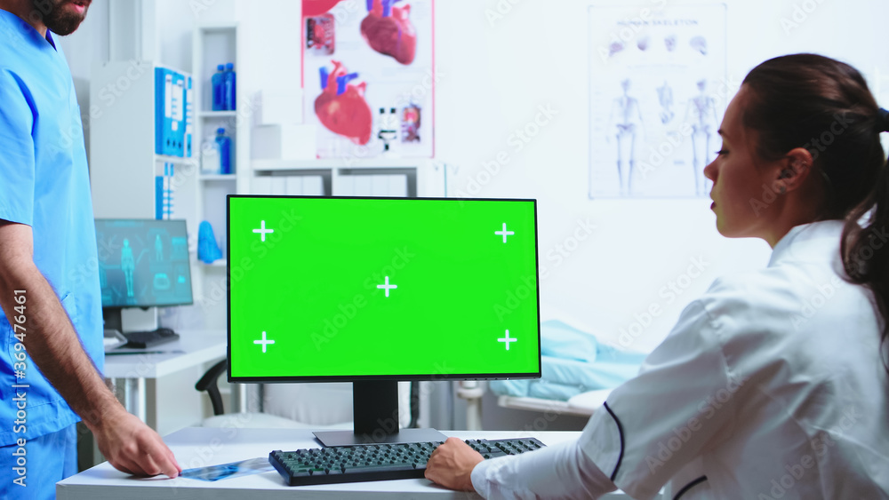 Aufkleber assistant giving doctor patient x-ray while she is working on computer with copy space green screen 