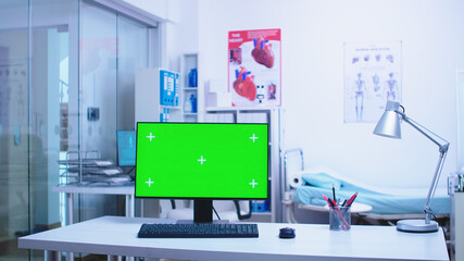 Chroma key on computer in hospital cabinet with medical personnel in the background. Computer with blank and copy space available on display of medicine specialist in clinic cabinet.
