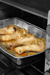 Chicken drumsticks with rosemary cooking in a foil tray in an oven grill