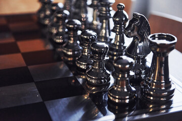 Chess board with metal figures on it indoors on the table at daytime