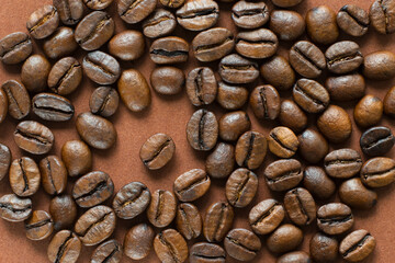 Coffee beans on brown background close up