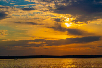 Obraz premium Sunset through the clouds over the water and ship on the water