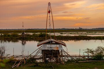 Fototapeta premium Traditional fishing tool or bamboo fish trap on sunset light, landscape silhouette.