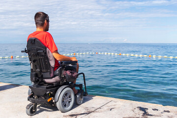 Man sitting in a wheelchair on the beach. Dangers of jumping into water from heights. Head and spine injury.