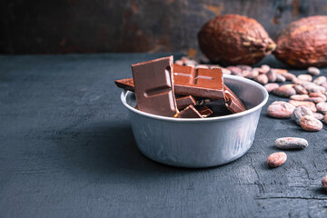 Dark chocolate pieces  and cocoa beans on table