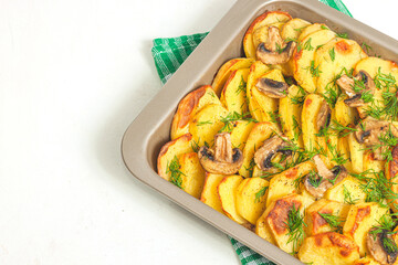 Potato wedges baked with mushrooms, herb oven roasted, with thyme, a close-up in a baking tray