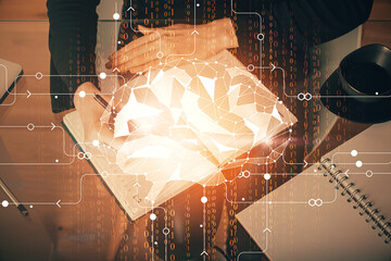 Double exposure of writing hand on background with brain hologram. Concept of learning.