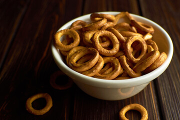 Small wheat bagels in white ceramic bowl on dark rustic table, traditional russian food