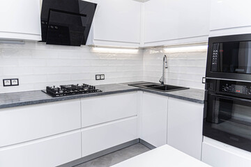 interior of white furniture of a compact kitchen, glossy cabinets with built-in household...