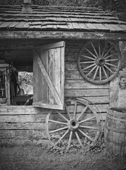 Obraz premium This is an antique scene of old wagon wheels near a log cabin outbuilding with a shutter window open.