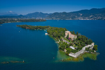 Obraz premium Aerial view of the island Garda, Lake Garda, Italy Aerial photography. Is the biggest island on Lake Garda. In the background Alps, blue sky.