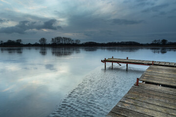 A wooden pier on a frozen lake and a evening sky