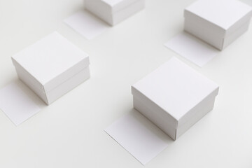 Mockup of four white boxes and business cards in front of them on the white background