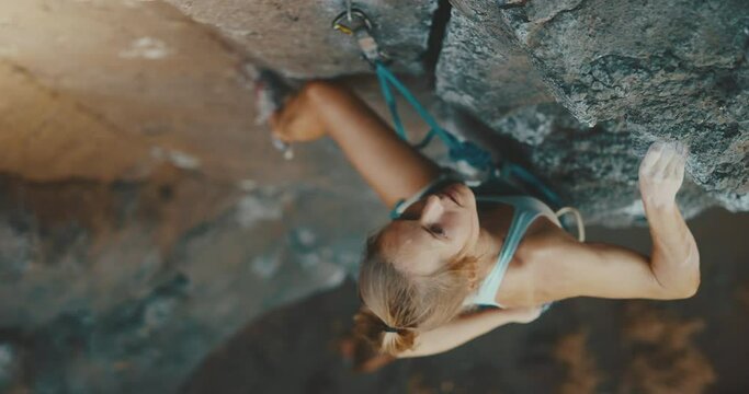 Incredible woman rock climbs mountain while friend belays her below, cinematic slow motion, fitness lifestyle
