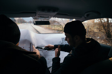 Two robbers planning and pointing on the blueprint(map) their objective while holding their guns.