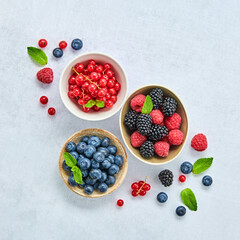Blueberry, raspberry, blackberry, redcurrant in bowl. Fresh blueberry, berries mix on marble. Red raspberry, mint creative composition. Colorful trendy concept, top view.