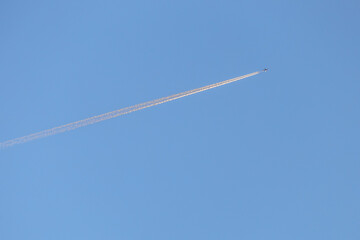 Flying airplane trail in a clear sky