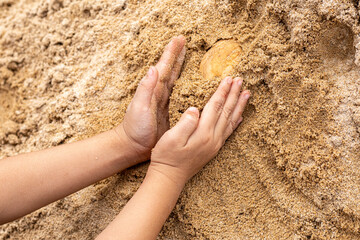 A boy playing on the sand pile at construction site.
