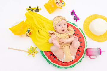 a smiling child with a swimming ring in a swimsuit, towel and sunglasses lies on a white isolated background. Holidays at sea with baby, concept