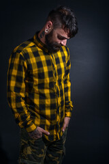 Profile portrait picture of a bearded man with tattoos on his face and neck in yellow black shirt