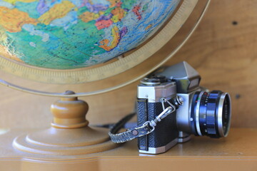 Close-up of antique cameras on a wooden table Globe as background selective focus and shallow depth...
