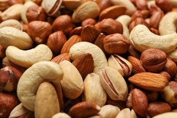 Different tasty nuts on whole background, close up. Vitamin food