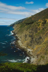 Beautiful Ragged Point vista looking north. Start of Big Sur scenic drive top tourist destination. Beautiful landscape or seascape, mountains meet Pacific Ocean   with cloudy blue skies, majestic.