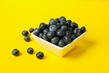 Square bowl with blueberry on yellow background