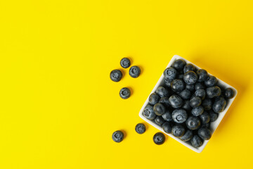 Square bowl with blueberry on yellow background