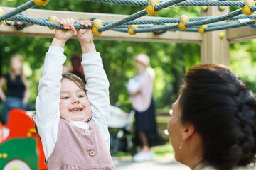 Little girl and her mother are playing on a playground