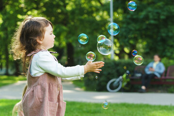  Little girl catching soap bubbles in a city park