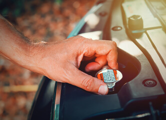 Man's hand opening the radiator cap of an SUV. Concept of car maintenance