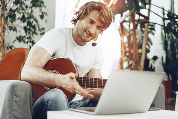 Young man watching guitar tutorial on his laptop