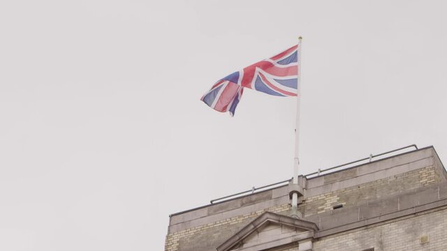 Slow motion low angle shot of the British flag waving. Bird flying by. Brexit