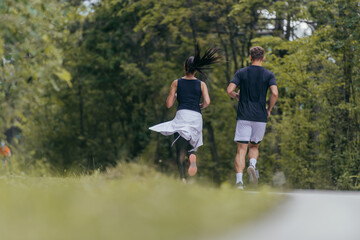 Obraz premium Young fit couple atheltes running on running road in a forest.