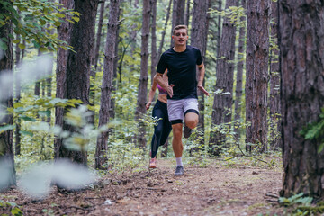 Strong male runner jogging for marathon on forest road