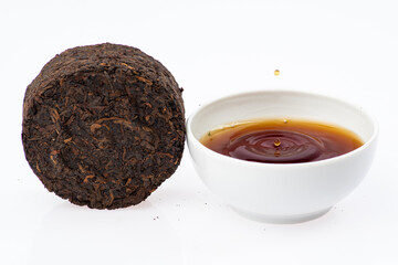 pressed black tea next to a cup of tea on a white background