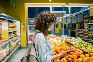 Woman in protective mask buys apples