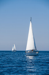Sailing ships yachts with white sails in open sea. Luxury boats on ocean.