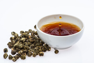 loose green tea next to a cup of tea on a white background