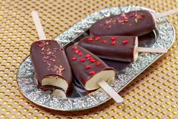 Homemade ice cream on a stick in dark chocolate icing.
