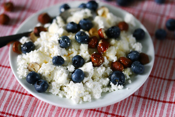 Selective focus. Macro. Plate with cottage cheese, blueberries, nuts and honey. Healthy diet. Keto breakfast or snack.