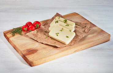 Sliced cheese, tomatoes and herbs in a cutting board