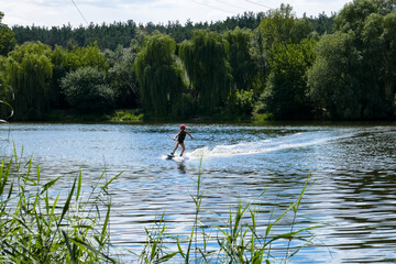 Fototapeta na wymiar Wakeboard, a man surfs in a lake near the city.