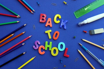 Lettering on blue surface back to school surrounded by stationery